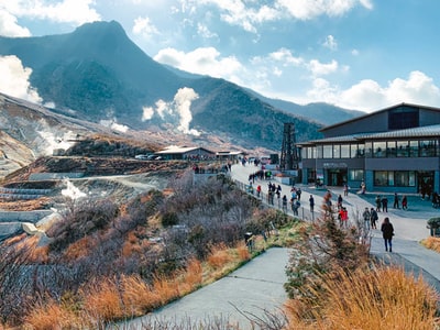 During the day, under the white clouds, mountains near a white and brown house
